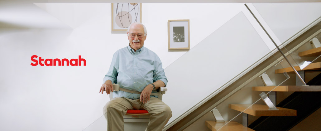 Cadeira elevatória Stannah a transportar pessoa idosa para o piso superior da casa.
